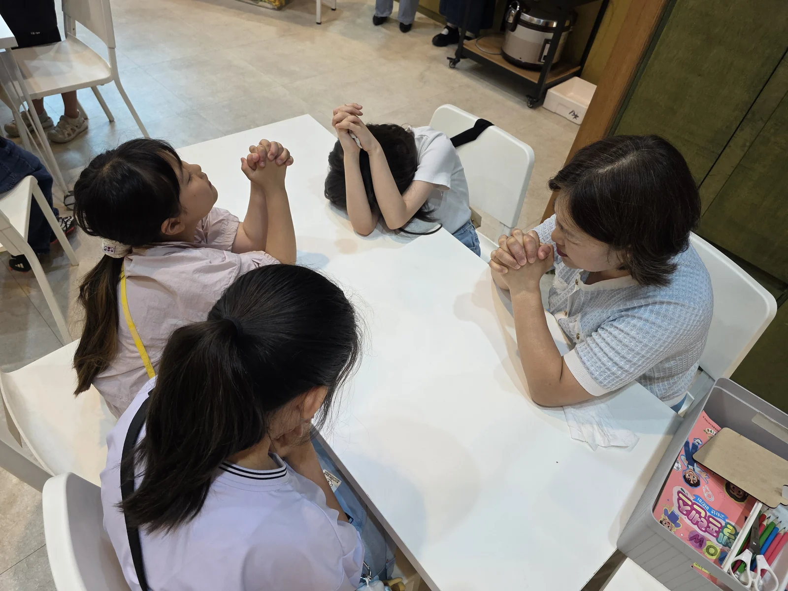 탁자에 둘러앉아 함께 고개를 숙이고 기도하는 모습
